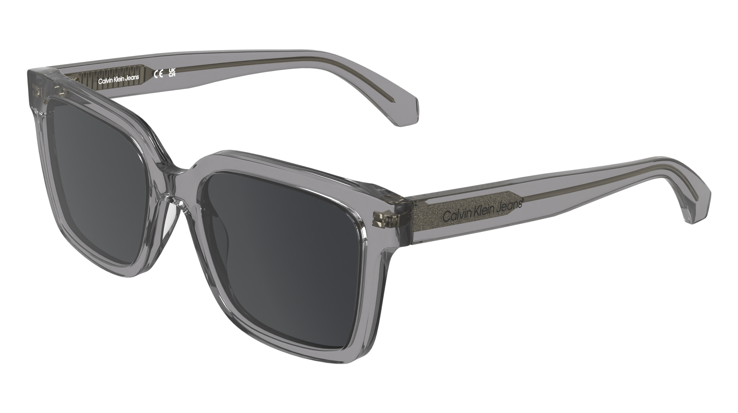 Lunettes de soleil Calvin Klein Jeans CKJ26301S dans le coloris Transparent Gris vers Gris Foncé, vue en trois quarts. Monture rectangulaire modifiée en gris translucide avec verres gris foncé, branches dotées d'un fil métallique brillant apparent et du logo Calvin Klein Jeans, fabriquées en acétate Color Shift photosensible aux UV.