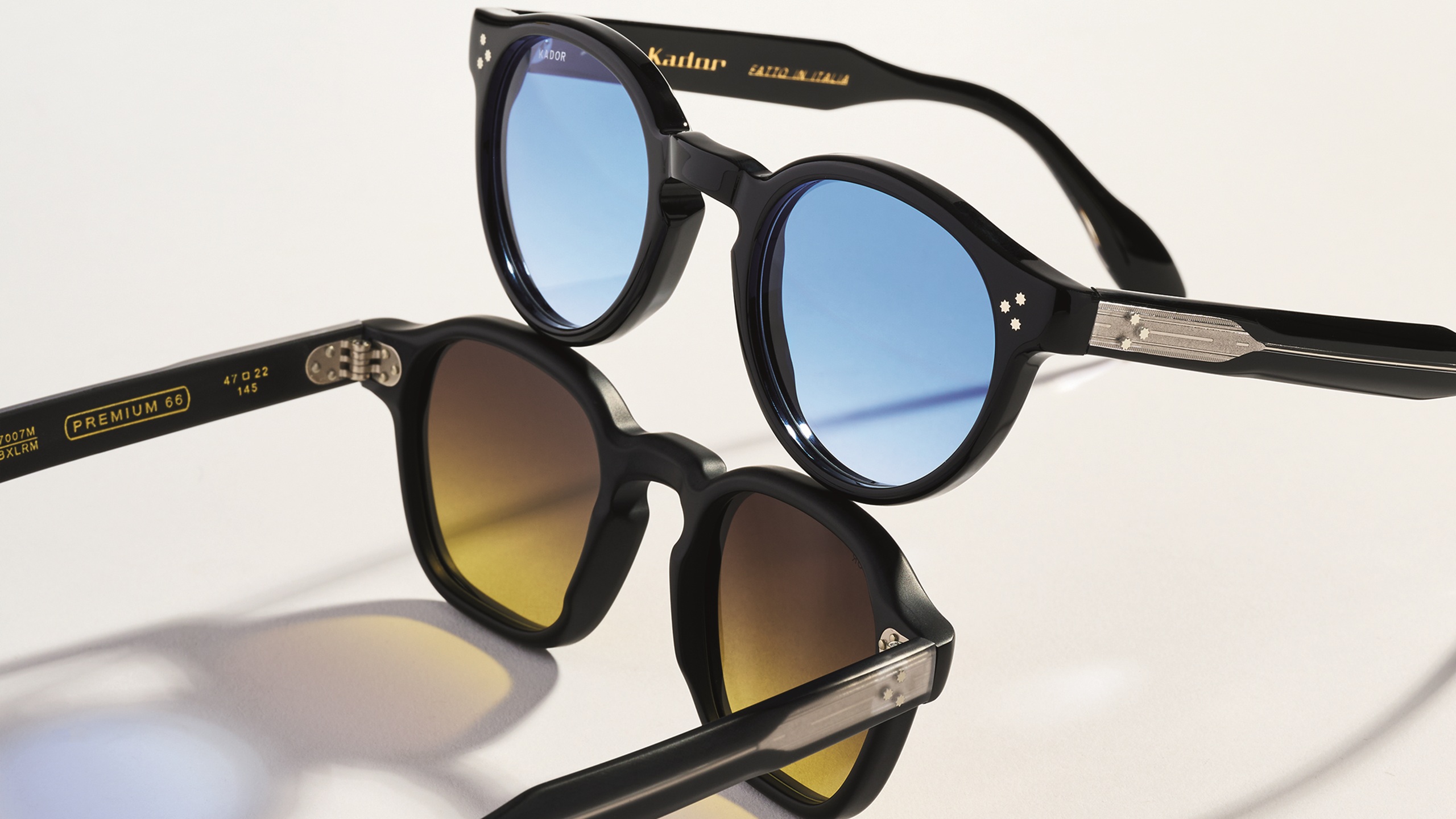 Deux paires de lunettes de soleil Kador superposées — la Premium 66 à monture carrée avec verres dégradés brun-jaune, et la Premium 99 à monture ronde avec verres bleu clair.