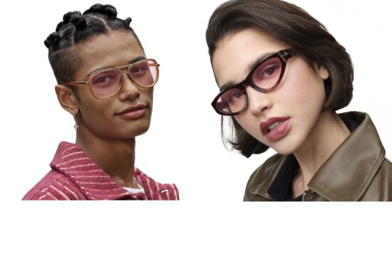Two models wearing Transitions® Color Touch™ lenses in the Ruby color. Left model wears gold aviator frames with pink-rose tinted lenses and a striped pink jacket. Right model wears tortoiseshell cat-eye frames with rose-gradient lenses and an olive leather jacket.