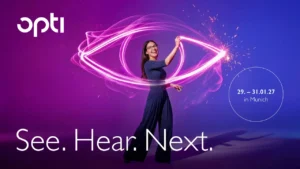 Visuel promotionnel pour opti 2027 présentant une femme souriante portant des lunettes sur un fond dégradé violet et bleu. Elle manipule un faisceau lumineux rose fluo qui dessine la forme d'un œil stylisé autour d'elle. L'image affiche le logo « opti », le slogan « See. Hear. Next. » et les dates de l'événement : « 29. – 31.01.27 in Munich ».