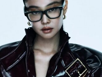 L'ambassadrice mondiale de Ray-Ban, Jennie, portant des lunettes rectangulaires noires Ray-Ban et une veste en cuir verni sombre dans la campagne de la marque