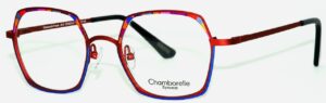 Chamborelle Eyewear metal eyeglasses frames in bold red with a bright blue inner rim accent. The oversized geometric square lenses feature multicolored mosaic patterned temples in red, blue, purple, and orange. Black rubber temple tips. Model CB-MOD-01, size 15-140. Made in France.