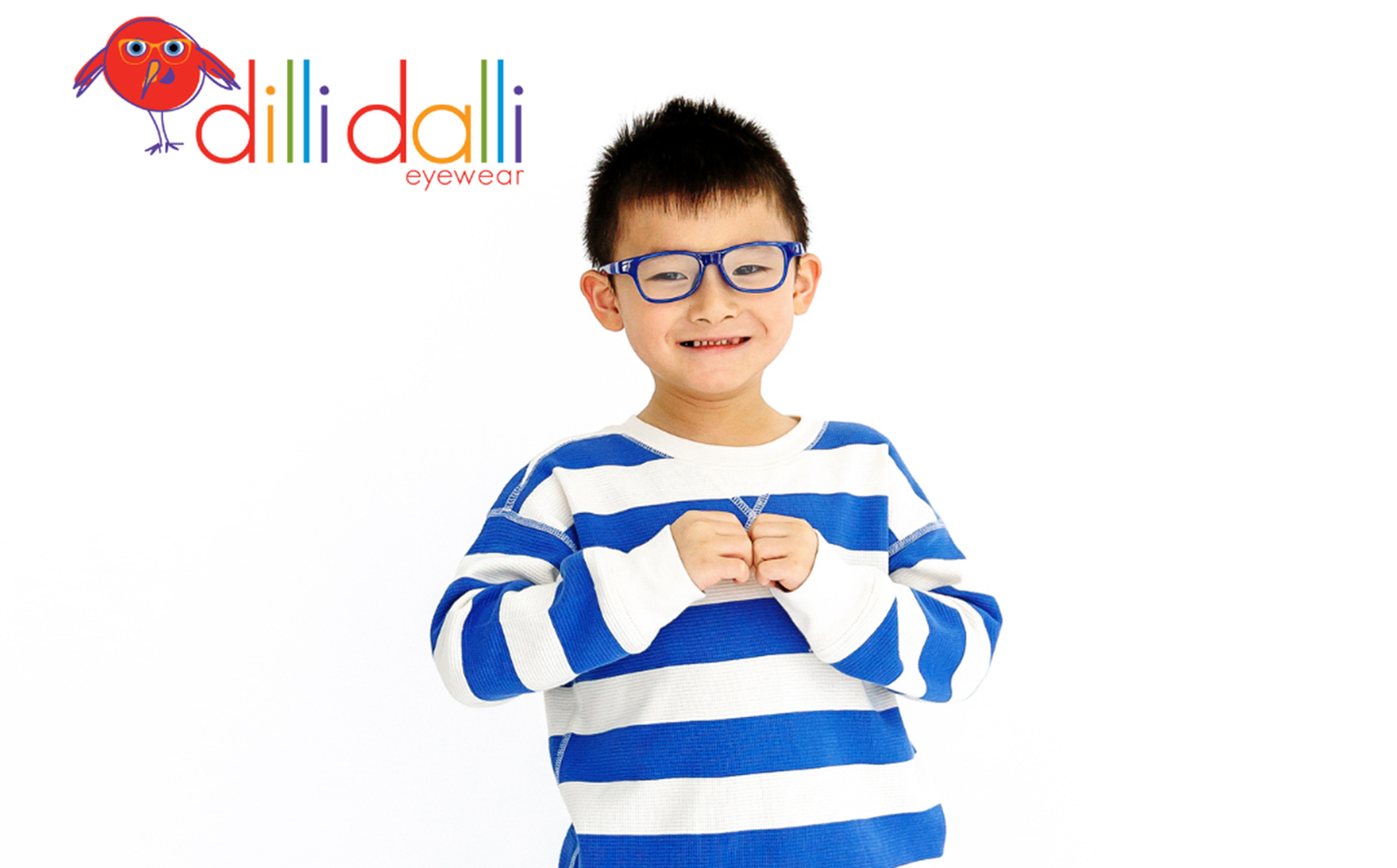 A young boy smiling and wearing blue Dilli Dalli Hero glasses, a blue and white striped sweater, and denim joggers.