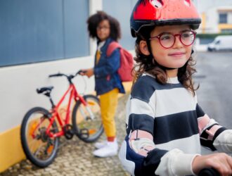 Young girl wearing glasses and a cycle helmet, smiling outdoors