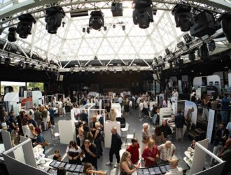 Panoramic view of the DaTE 2025 trade show floor filled with visitors and exhibitor stands under a large glass dome roof