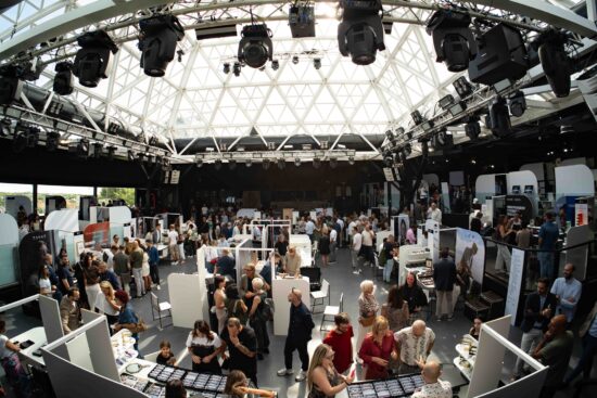 Panoramic view of the DaTE 2025 trade show floor filled with visitors and exhibitor stands under a large glass dome roof
