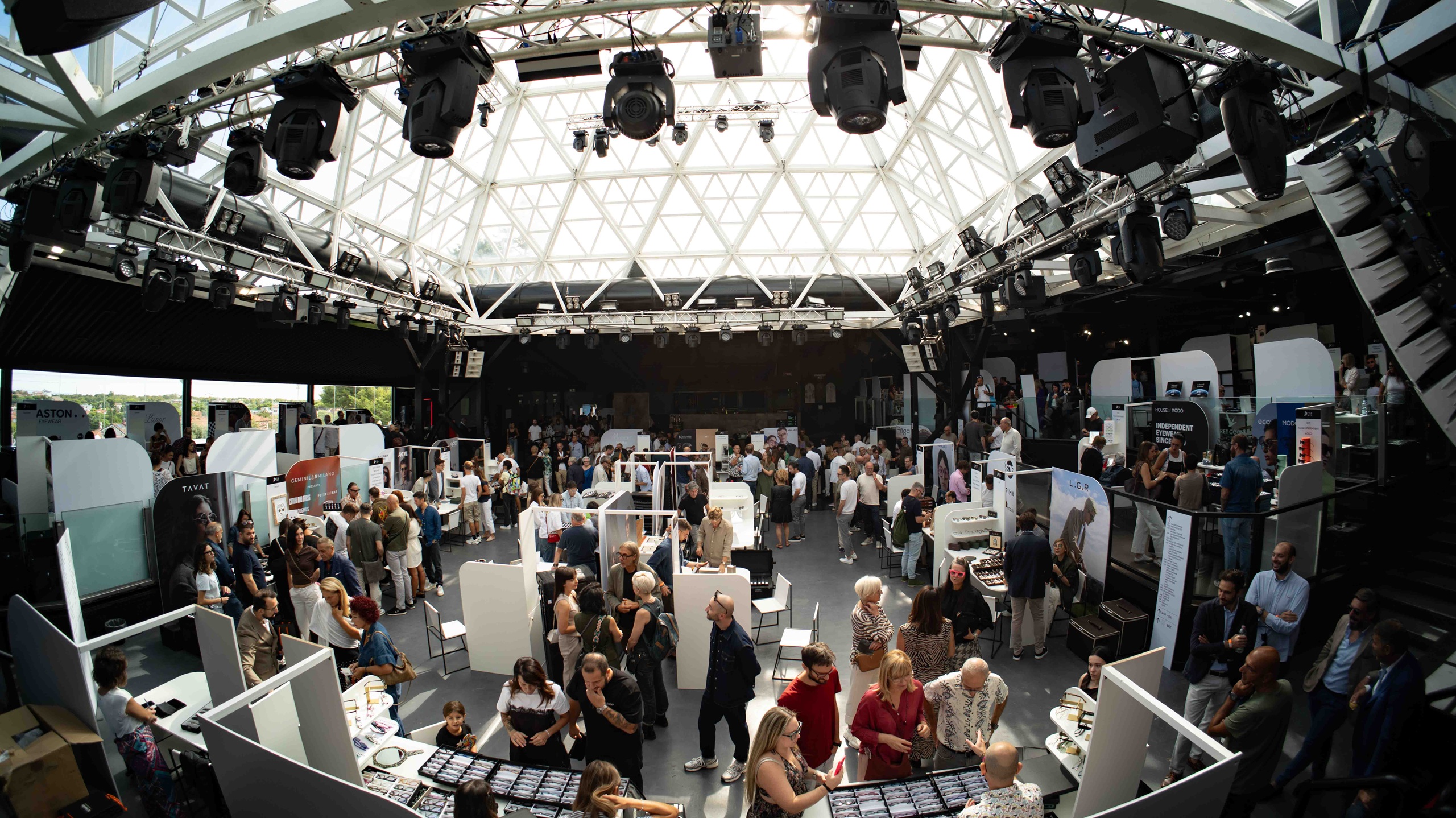 Panoramic view of the DaTE 2025 trade show floor filled with visitors and exhibitor stands under a large glass dome roof