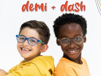 Two smiling boys sitting back-to-back wearing Demi + Dash children's eyeglasses frames against a white background with colorful rainbow graphic accents. The Demi + Dash logo appears at the top in playful red script.