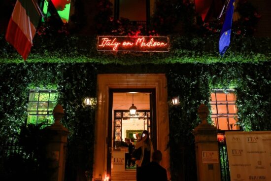 Entrance of the Italy on Madison event venue at night, with a red neon sign and ivy-covered facade