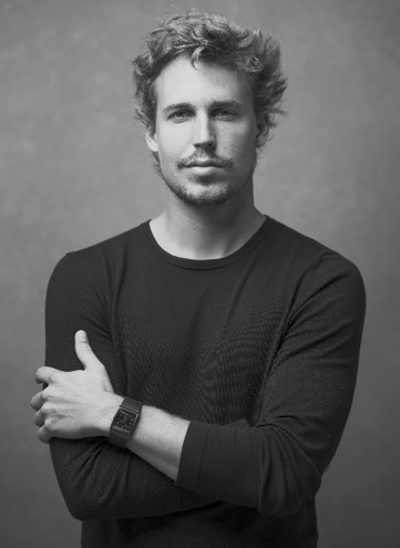 Black and white portrait of Joachim Froment, President of the SILMO d'Or 2026 jury, arms crossed, wearing a dark textured crewneck sweater and a watch, against a neutral studio background.