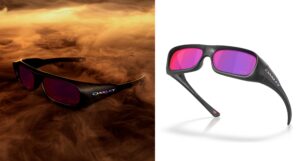 A split-screen product image of the Oakley Permian Kylian Mbappé Signature Series. The left side displays the bold, deep-set black frames emerging from a golden-orange smoke. The right side shows the glasses on a white background, showcasing the "KM" logo etched on the purple Prizm Road lens and the iridescent Oakley branding on the temple.