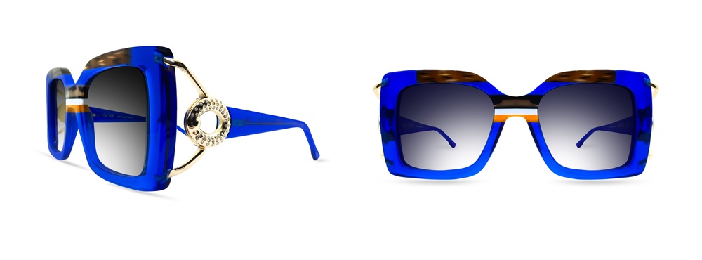 Lunettes de soleil Ultra Limited Torcello en acétate transparent bleu électrique avec insertions en écaille de tortue et ambre, branches en métal doré ornées d'un détail circulaire d'inspiration joaillière avec détails en cristal, et verres bleu-gris dégradés. Présentées de profil et de face sur fond blanc.