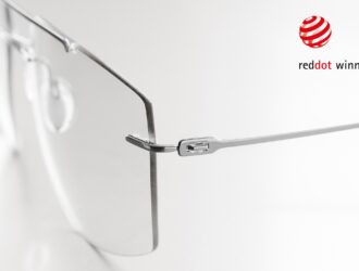 Close-up detail of the Silhouette The Refined frame hinge and temple connection in brushed titanium, with the Red Dot Winner 2026 logo displayed in the upper right corner.