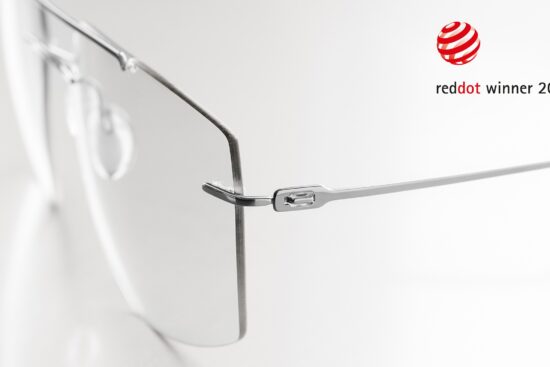 Close-up detail of the Silhouette The Refined frame hinge and temple connection in brushed titanium, with the Red Dot Winner 2026 logo displayed in the upper right corner.