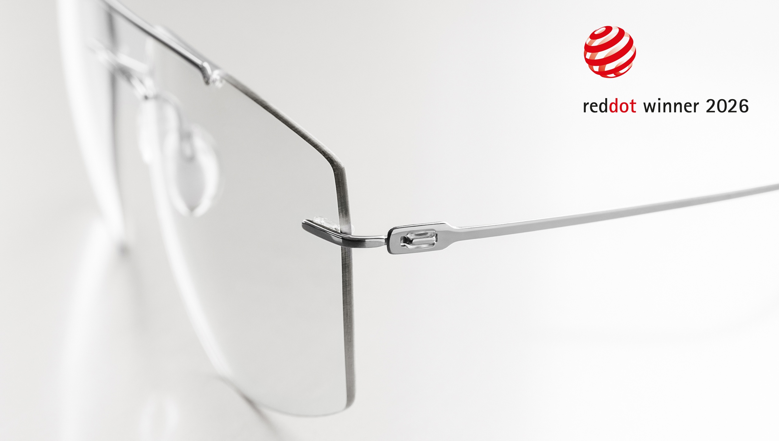Close-up detail of the Silhouette The Refined frame hinge and temple connection in brushed titanium, with the Red Dot Winner 2026 logo displayed in the upper right corner.