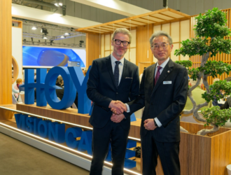 John Goltermann Lassen, PDG de HOYA Vision Care, et Motoki Ozawa, Président et PDG de NIDEK, se serrent la main au stand d'exposition de HOYA Vision Care, symbolisant le renouvellement de leur partenariat stratégique mondial.