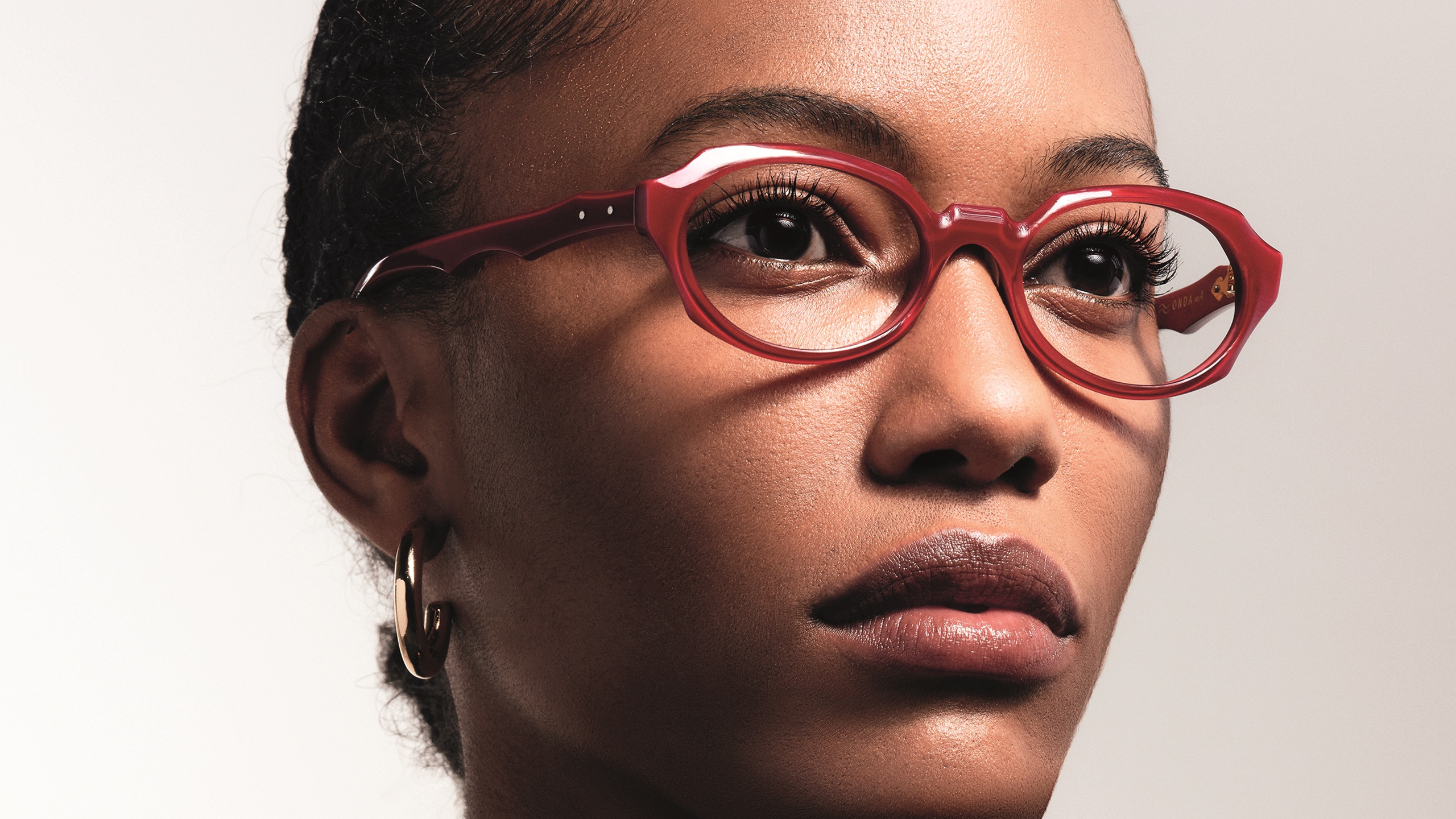 Portrait rapproché d'une femme portant des lunettes de vue en acétate rouge brillant de la collection ONDA.