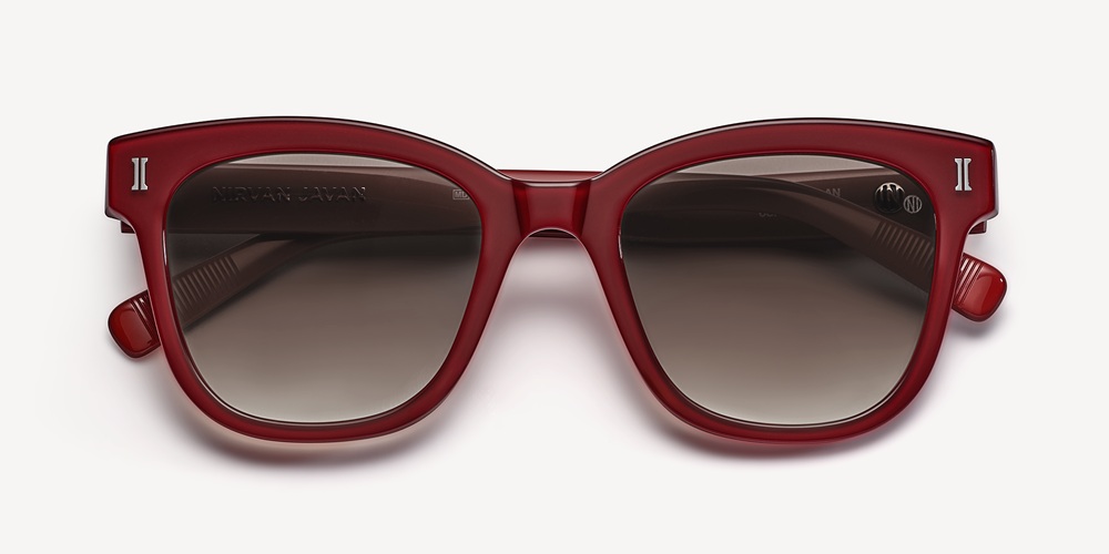 Une paire de lunettes de soleil en acétate rouge foncé, dotée d'une monture carrée audacieuse et de verres dégradés, présentée à plat sur fond clair.