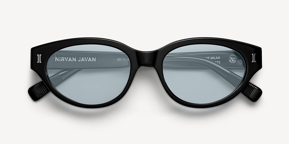 A pair of glossy black acetate sunglasses featuring a softly rounded silhouette and light blue lenses, shown flat against a light background.