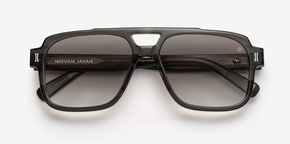 Une paire de lunettes de soleil de style aviateur à double pont en acétate gris translucide, avec des verres dégradés, présentée à plat sur fond clair.