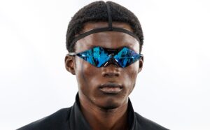 Front view of a model wearing the handcrafted Oakley Moonbase1 prototype glasses with a geometric wrapped frame and vibrant blue mirror lenses at Paris Fashion Week.