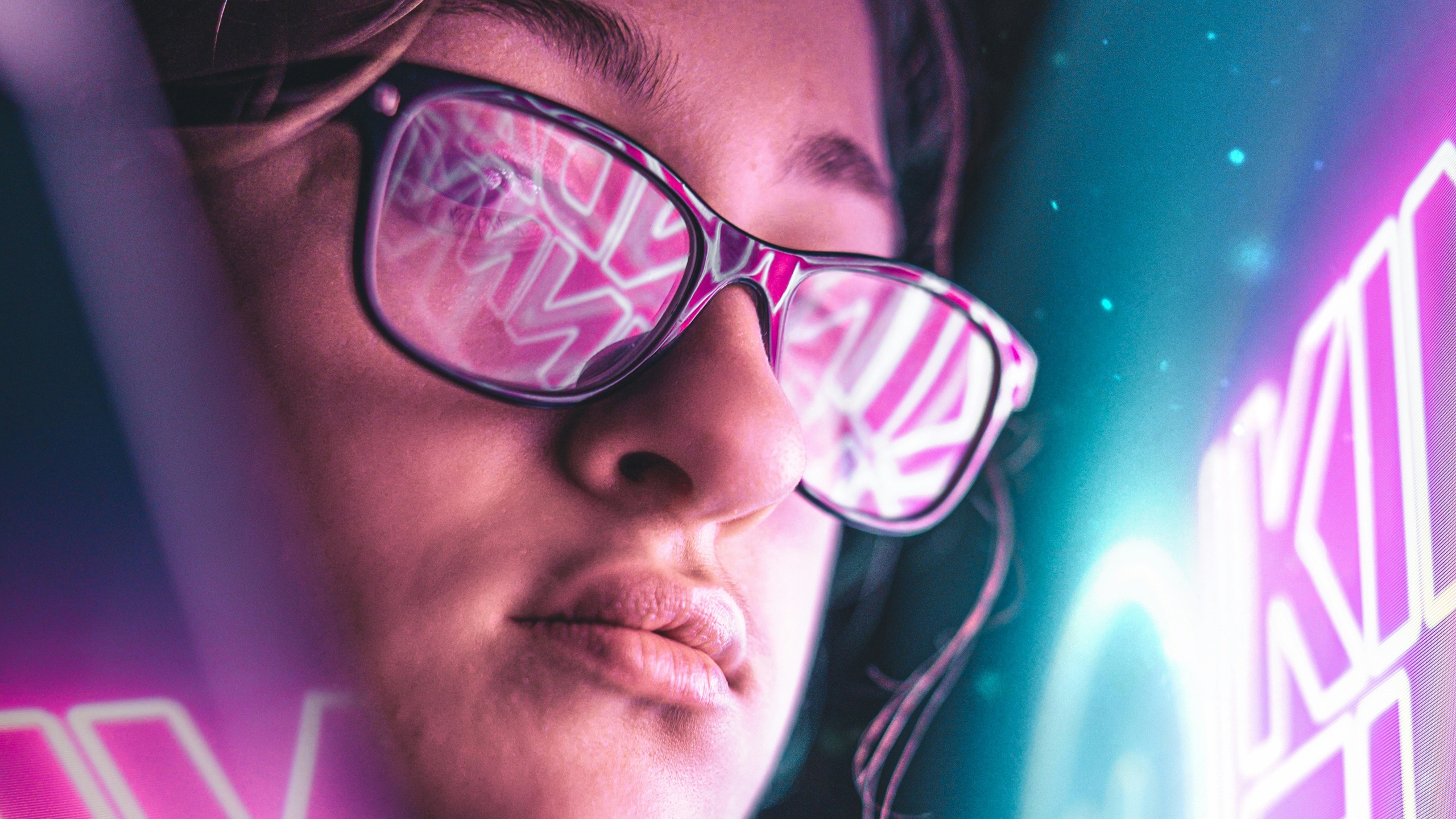 Close-up of a person wearing glasses that reflect vibrant, pink neon text, set against a cyberpunk-style blue and purple background.