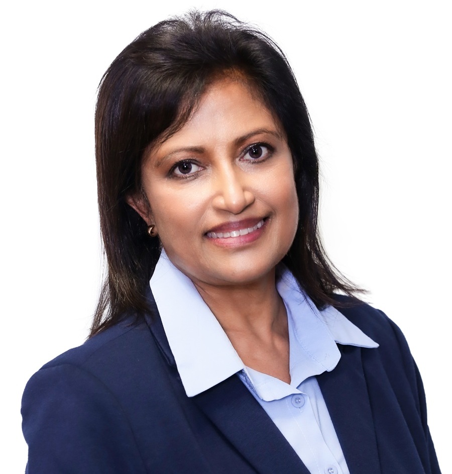Headshot of Prof. Vanessa Moodley smiling, with shoulder-length dark hair, wearing a blue blazer and a light blue collared shirt against a white background.