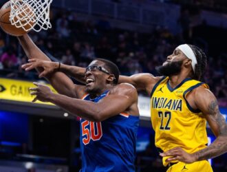 Trey Jemison III wearing clear protective eyewear while driving to the basket for a layup, closely defended by an Indiana Pacers player during an NBA game.