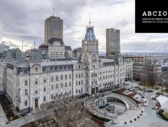 Vue aérienne de l'Hôtel du Parlement de Québec, un imposant édifice de style Second Empire en pierre grise, entouré de ses jardins en hiver avec des traces de neige. Des gratte-ciels modernes se dressent en arrière-plan sous un ciel nuageux. Le logo de l'ABCIOQ apparaît dans un encadré noir en haut à droite de l'image.