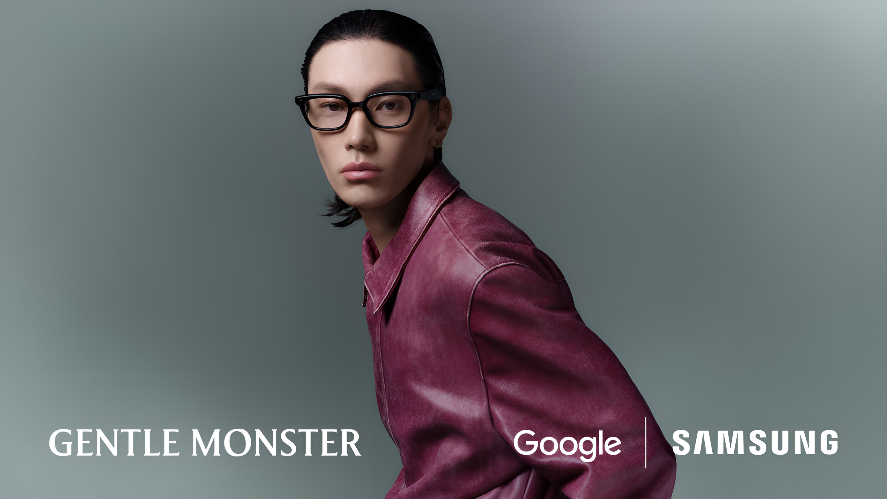 Lifestyle portrait of a male model wearing the black Samsung Intelligent Eyewear (Gentle Monster design) and a maroon leather jacket. The image emphasizes the thin design and stylish appearance. logos for Gentle Monster, Google, and Samsung are displayed.