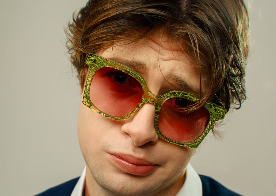 Portrait d'un homme portant des lunettes de soleil durables Ferilli Eyewear avec une monture verte et des verres rouges