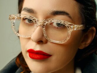 Portrait en gros plan d'une femme portant des lunettes de vue éco-responsables Ferilli Eyewear transparentes avec du rouge à lèvres rouge