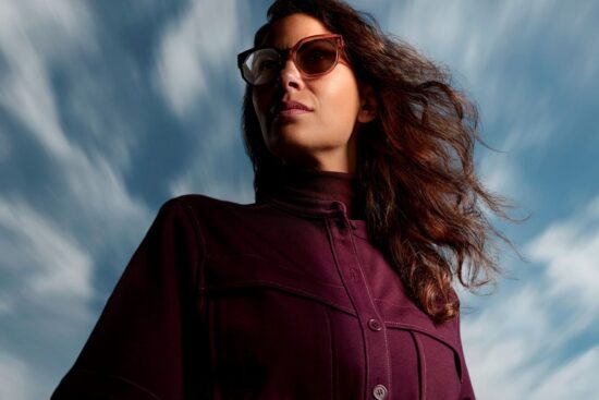 Woman wearing HOYA Sensity 3 light-adaptive sunglasses with Bronze Brown tint outdoors against a dramatic sky