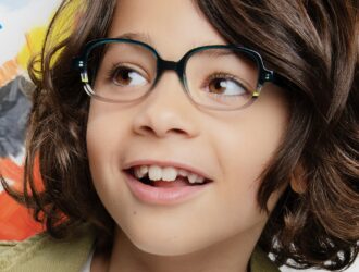 Smiling child wearing J.F. Rey Kids IMAGINE teal acetate glasses, colorful creative background