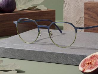 Lunettes bicolores bleu et vert LOOK Lamina modèle 10946 présentées sur un bloc de pierre grise avec des figues dans une mise en scène lifestyle moderne.