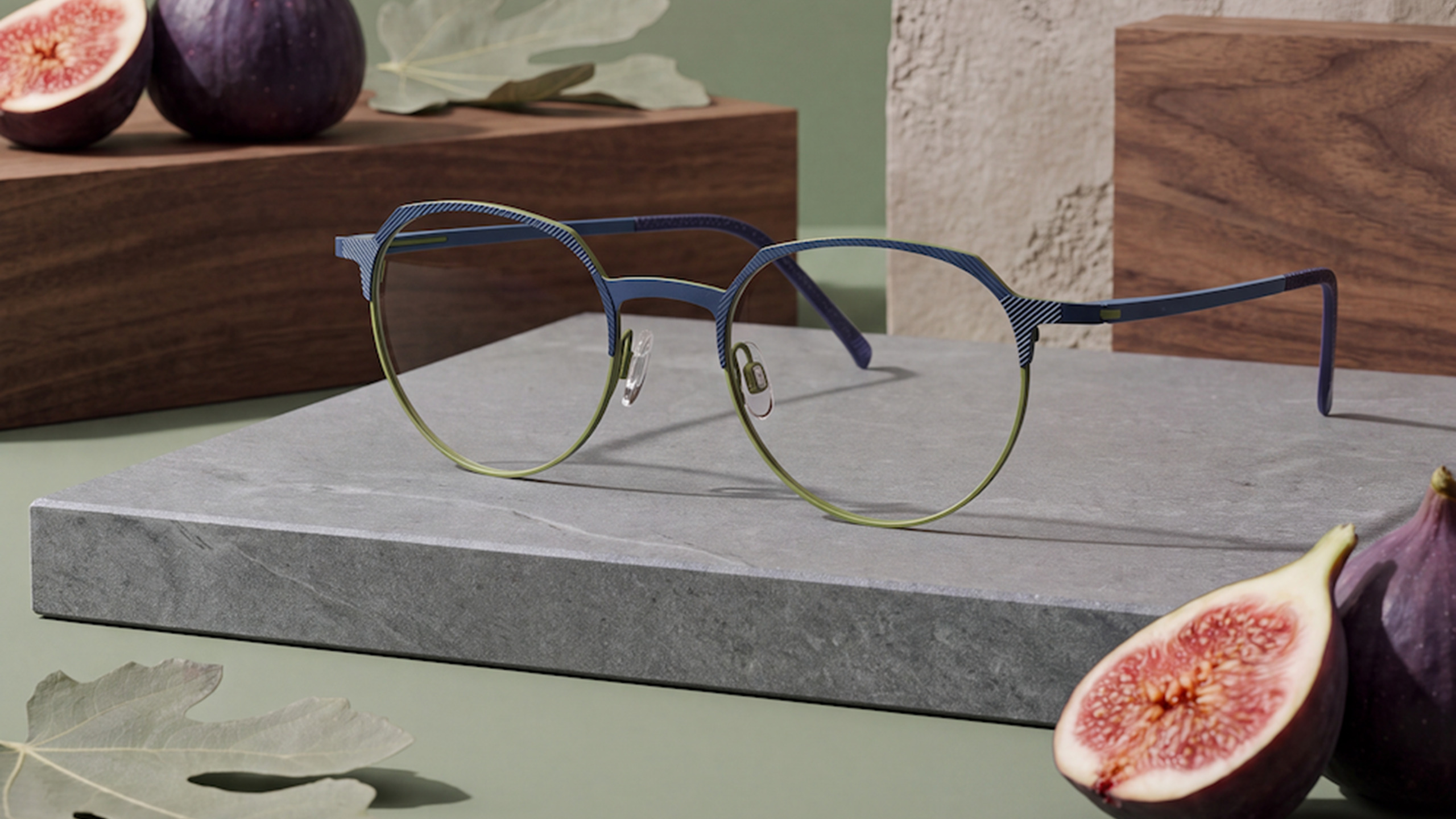 LOOK Lamina model 10946 two-tone blue and green eyeglasses displayed on grey stone block with figs in modern lifestyle setup