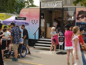 Transitions® branded pop-up booth on Grand Allée during the Festival d'été de Québec, with visitors exploring lens colours and style options.