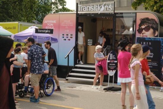 Transitions® branded pop-up booth on Grand Allée during the Festival d'été de Québec, with visitors exploring lens colours and style options.