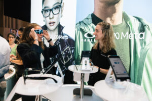 A visitor trying on smart glasses at the EssilorLuxottica booth during VivaTech 2026, with an Oakley Meta AI display backdrop
