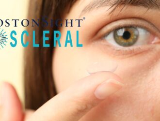 Close-up of a person holding a clear BostonSight SCLERAL lens near their eye