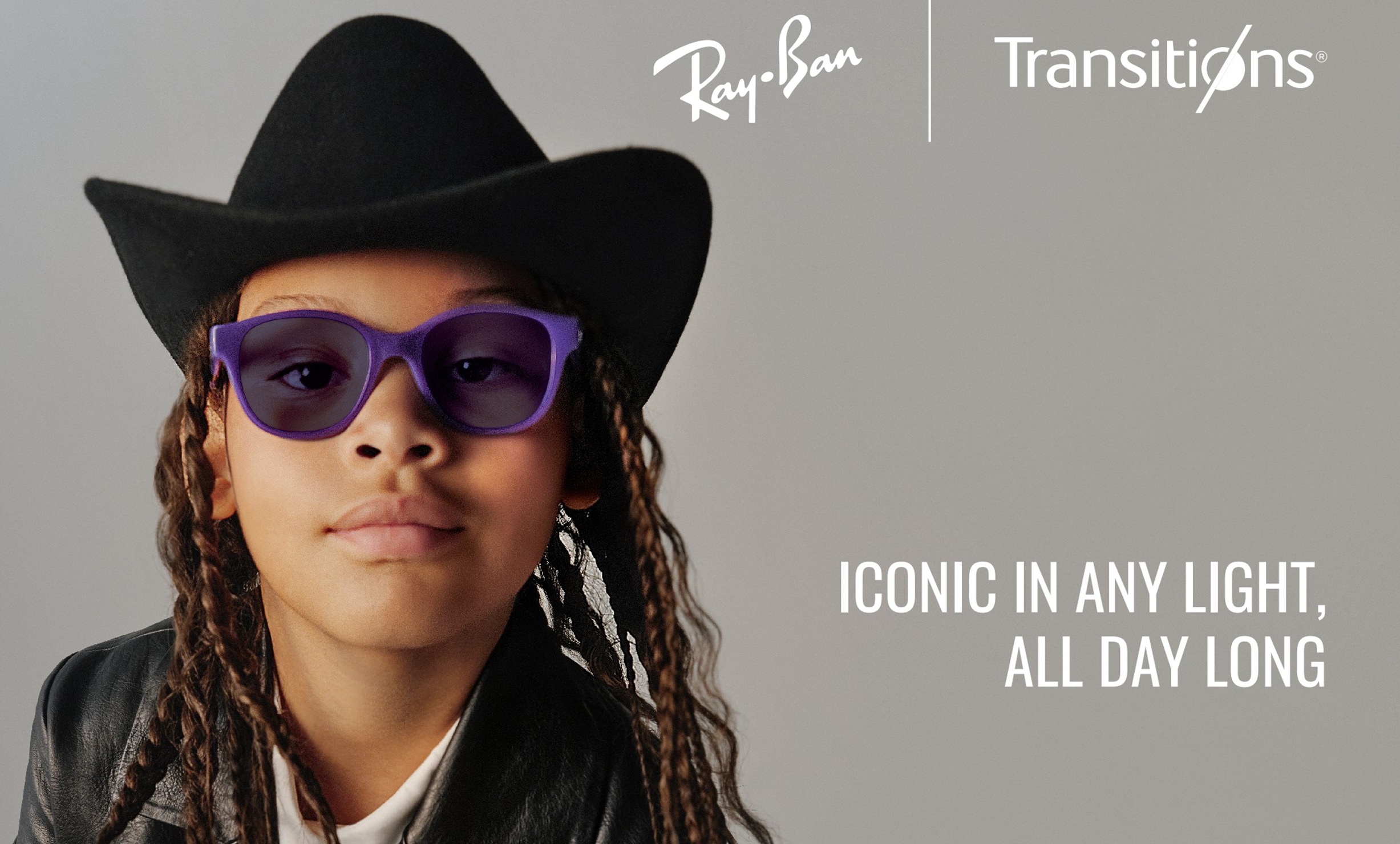 Child wearing purple Ray-Ban glasses with Transitions photochromic lenses and a cowboy hat with text reading Iconic in any light, all day long