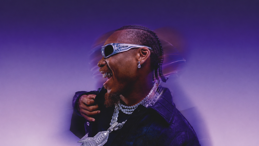 Justin Jefferson de profil portant les lunettes de soleil Oakley Highland argentées à effet verre translucide et des chaînes en diamants sur fond violet.