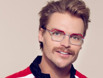 Model wearing OGI geometric metal glasses featuring silver rims and red-orange brow accents.