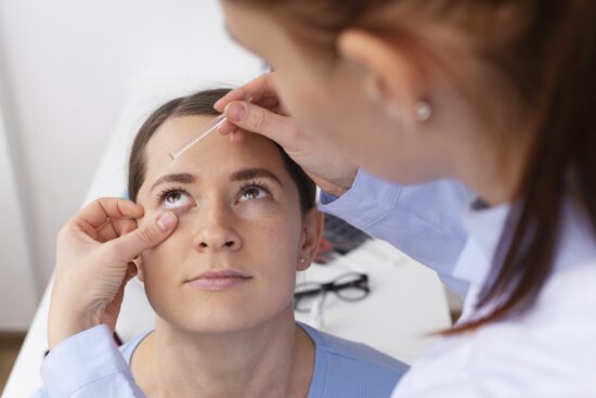 Ophtalmologue administrant des gouttes oculaires à une patiente lors d'un examen pour la sécheresse oculaire