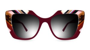 Front view of Ultra Limited CHIOGGIA oversized cat-eye sunglasses featuring dark gradient lenses, a deep burgundy lower rim and bridge, and geometric multi-colored striped acetate detailing along the upper brow line and outer corners.