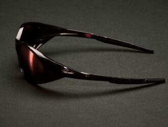 Side view of Cactus Jack x Oakley Eye Jacket Redux sunglasses in exclusive dark colorway on dark surface