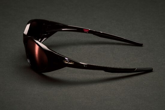 Side view of Cactus Jack x Oakley Eye Jacket Redux sunglasses in exclusive dark colorway on dark surface