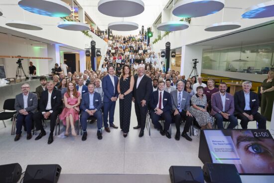 Group photo at the opening event for The Vision Centre, showcasing the large audience on tiered seating in the modern atrium space.
