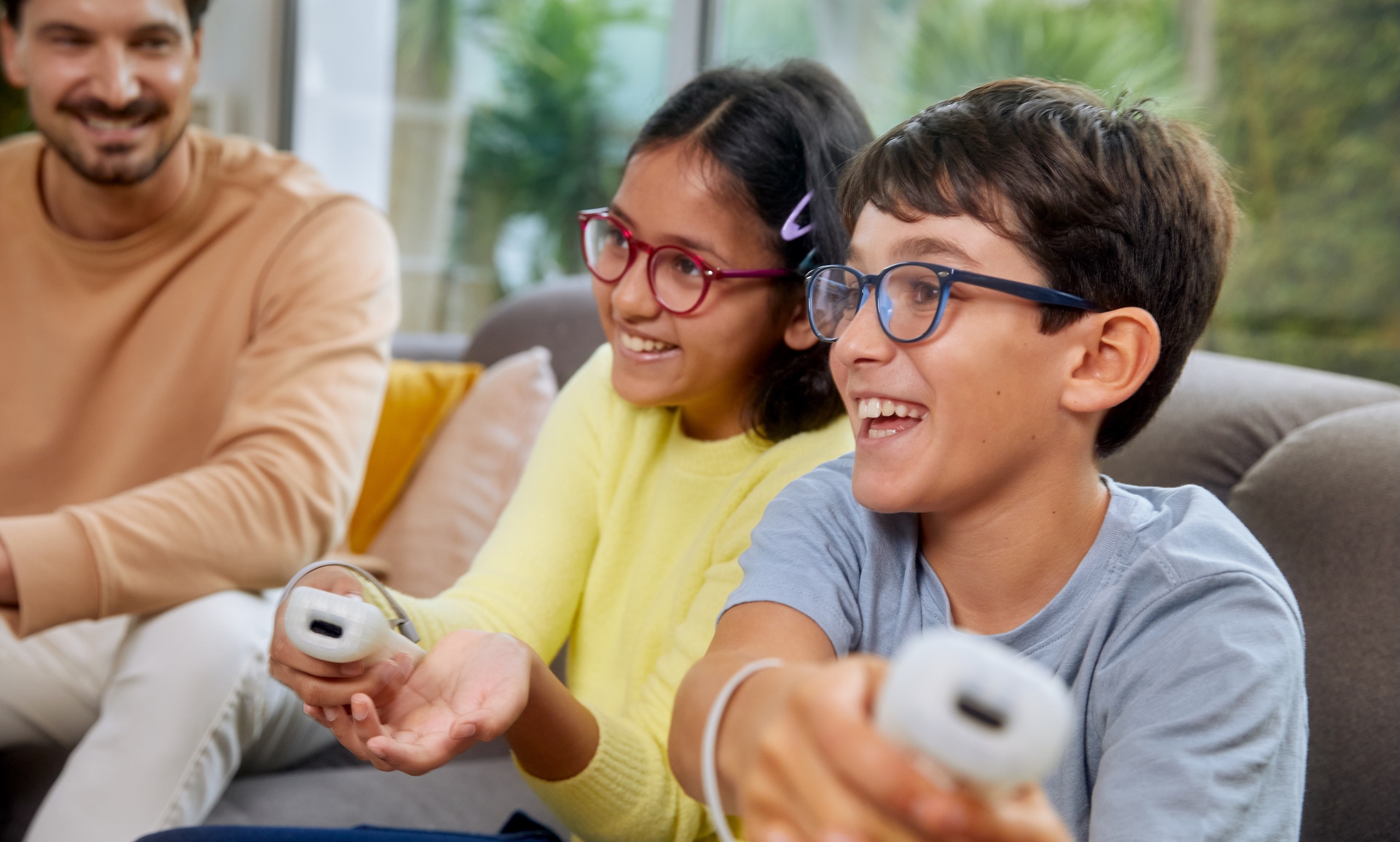 Deux enfants portant des verres de lunettes de contrÃ´le de la myopie DOT sourient en jouant confortablement Ã  des jeux vidÃ©o Ã  la maison, dÃ©montrant ainsi la clartÃ© de la vision pendant les activitÃ©s ludiques.