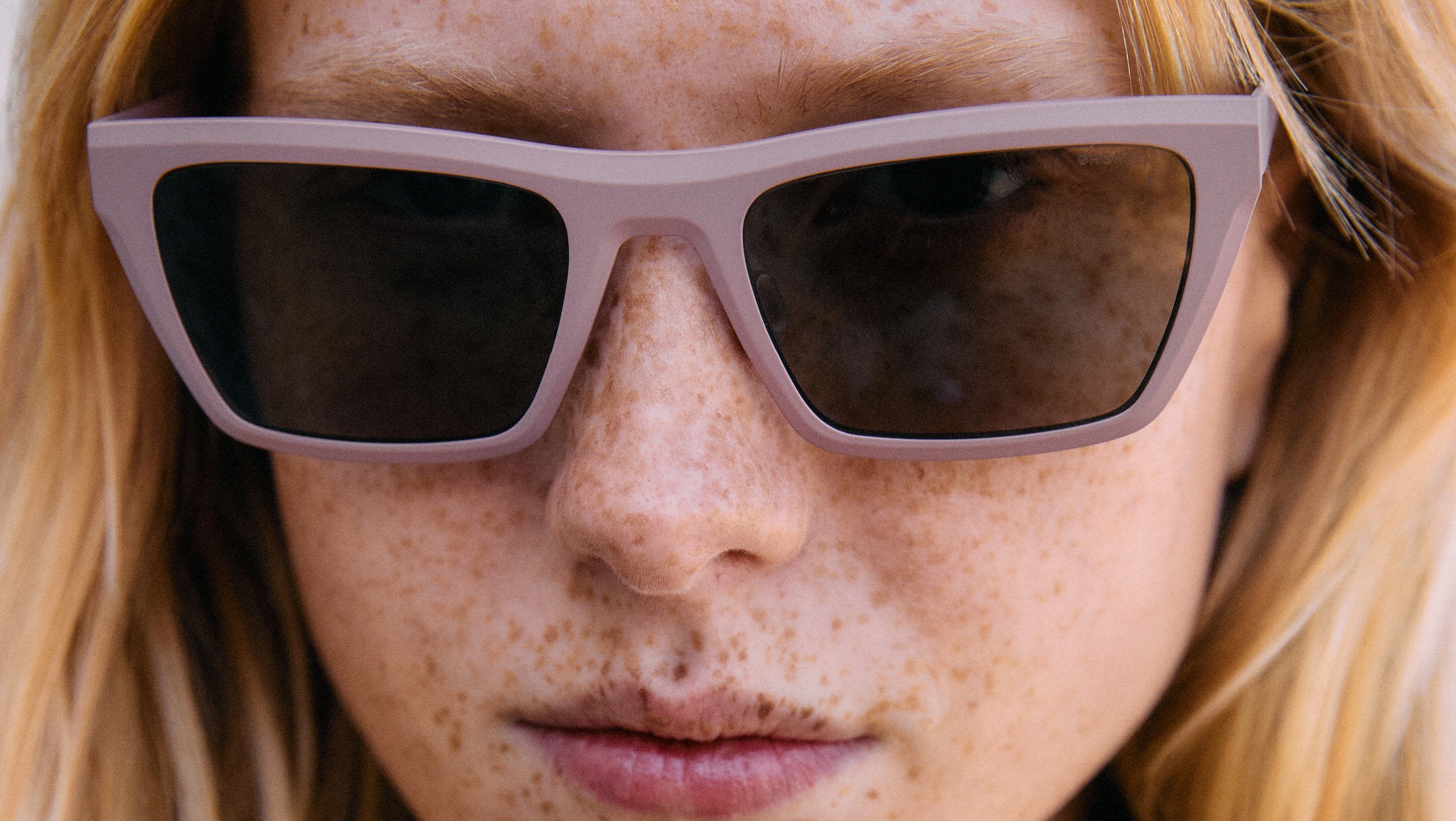 Extreme close-up on a person wearing the new Ørgreen Sheet Titanium SUN sunglasses in matte lavender with dark lenses.